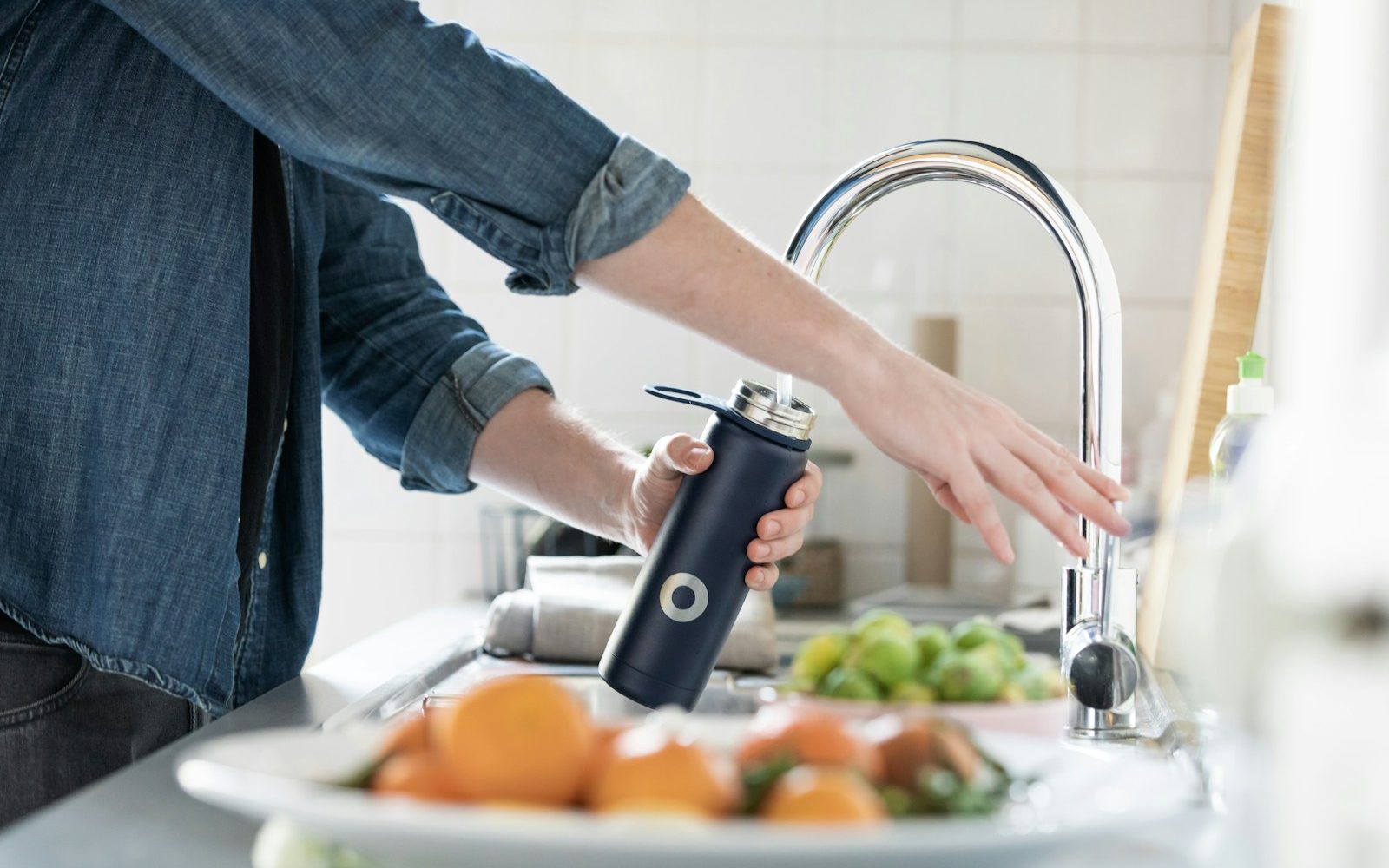 Person filling water bottle with high quality drinking water from tap
